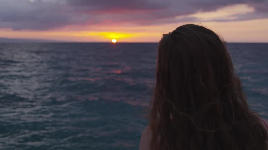 Woman watches sunrise over the ocean