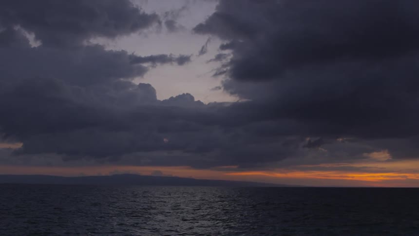 Dark clouds loom over an expanse of the ocean