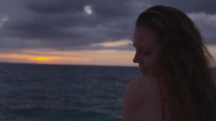 Woman standing near ocean at sunset
