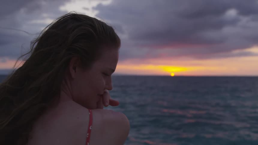 A woman smiles off to the right near the ocean