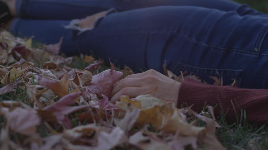 Woman lays on the ground touching leaves