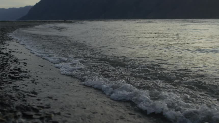 An ocean wave crashes into the beach
