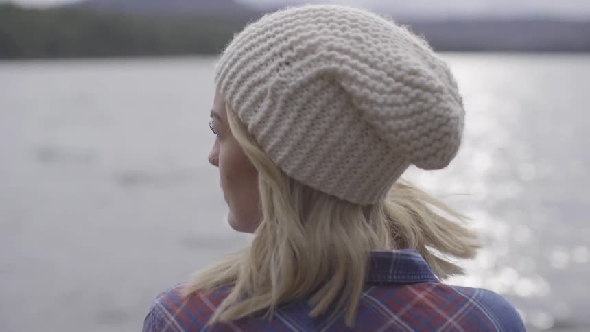 A blonde white woman looks across a lake