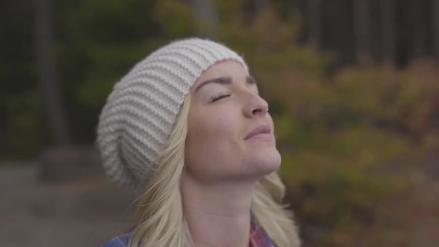 Woman in beanie feels wind on face while tilting head up