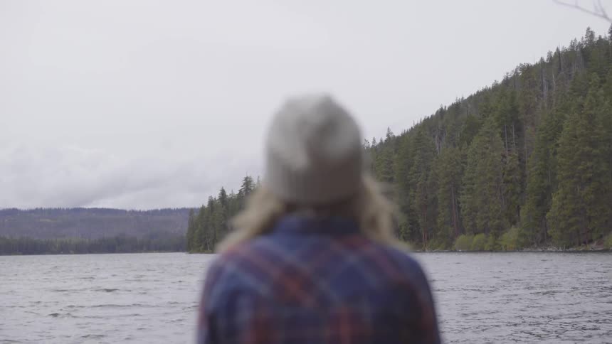 A woman stares off into the distance of the water