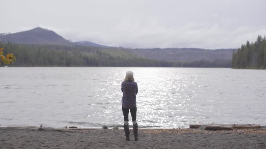 Woman stands on lake shore