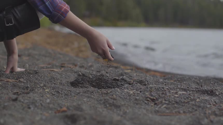 A woman grabs the dirt near the water