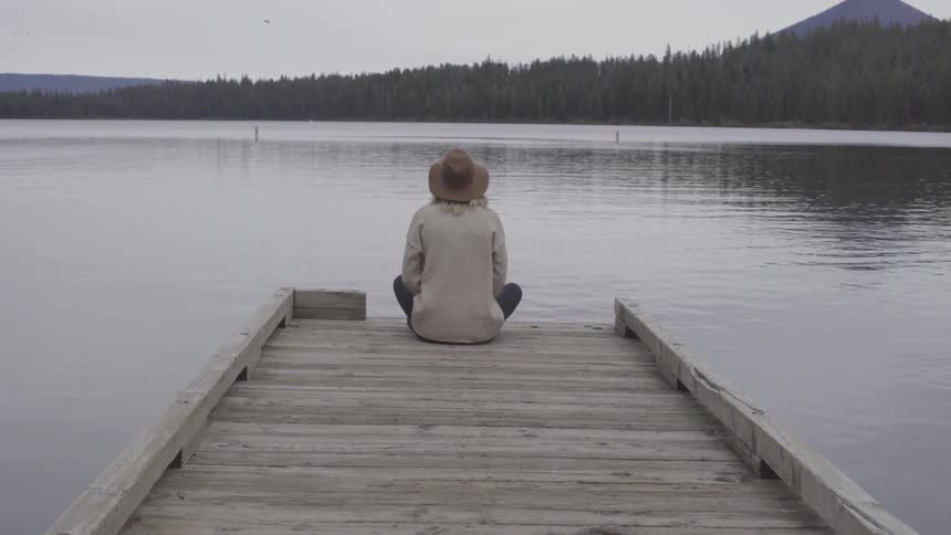 A woman sits at the edge of the dock