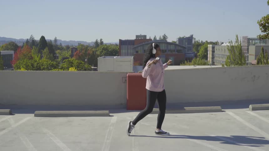 Woman dances outside while wearing headphones