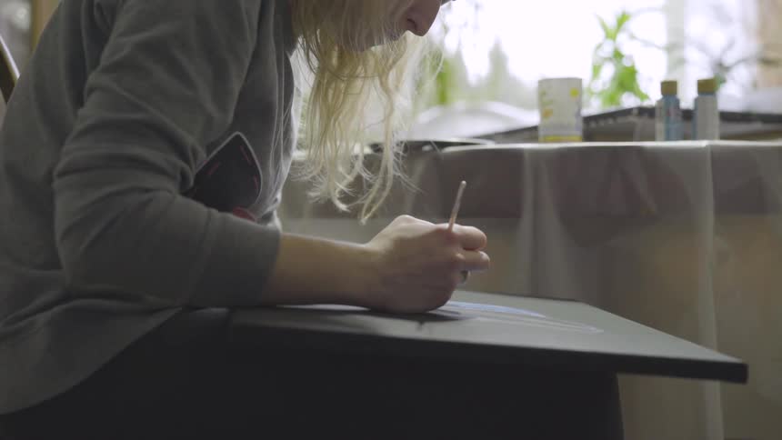 A woman paints on a black canvas