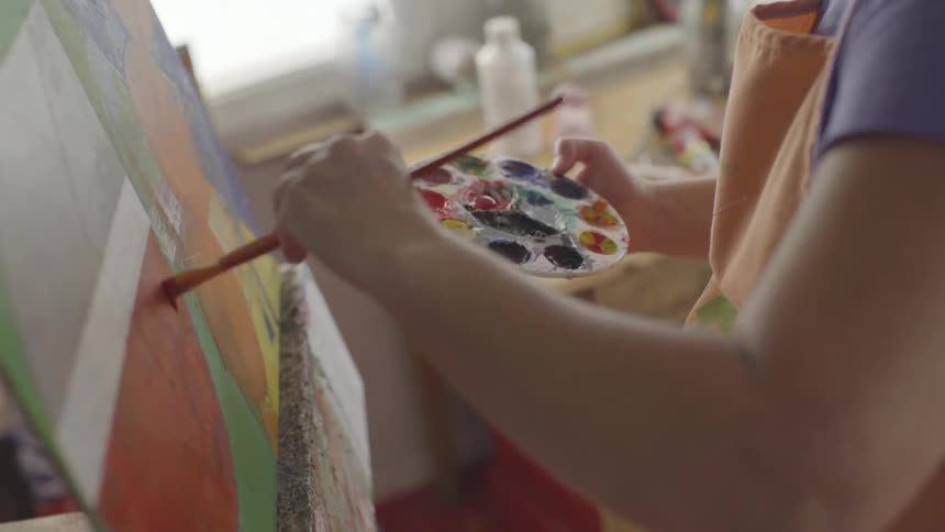 A painter making strokes with red paint on a painting