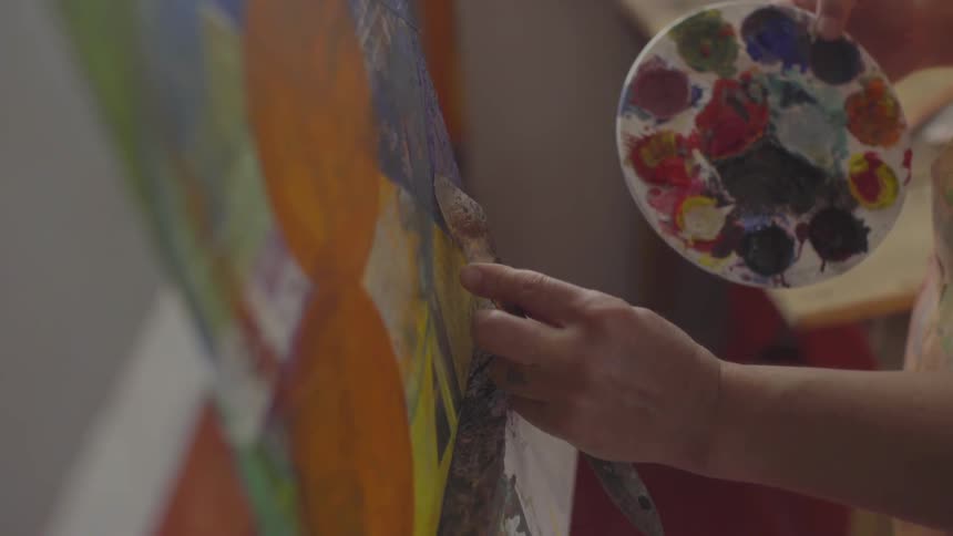 A woman is painting on a canvas in an art studio