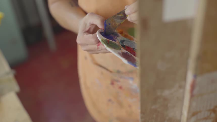 A woman is painting with oil paints in an art studio