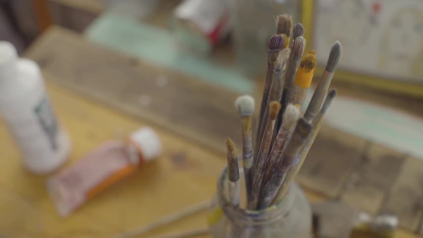 Paint brushes in a jar sitting on a table