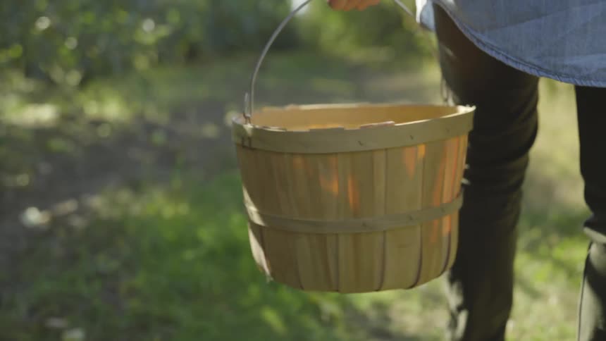 A person carrying a wicker basket outdoors during the day