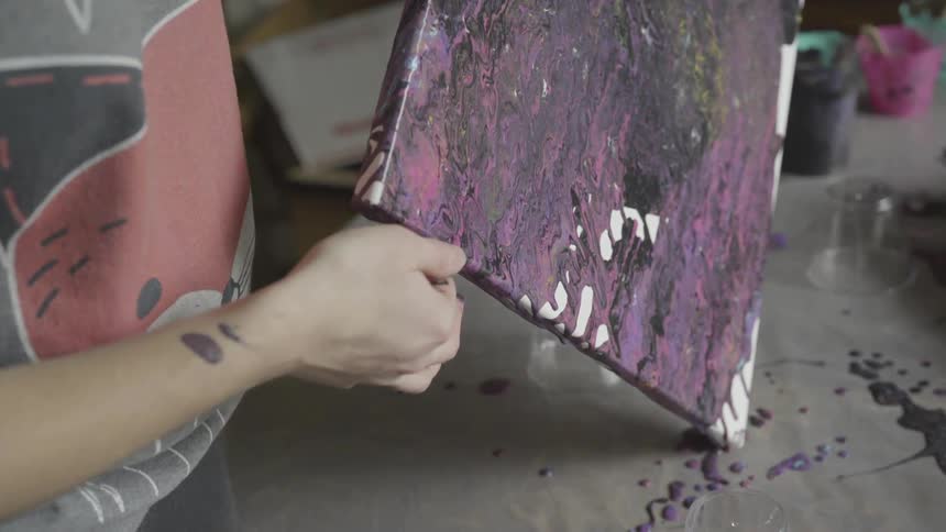A painter tilting a painting so that the paint runs
