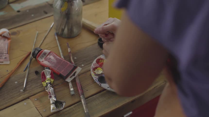 Person squeeze a tube of paint onto a palette