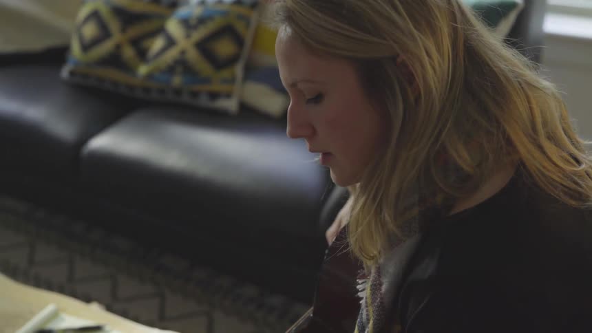A woman plays the guitar in a living room