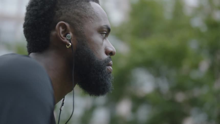 Black man sitting listening to music and holding a basketball