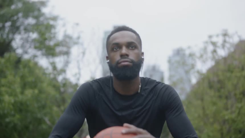 Man sitting down spinning a basketball in his hands and listening to music