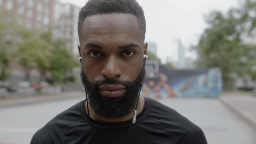 Man looks up at the camera while standing on a basketball court