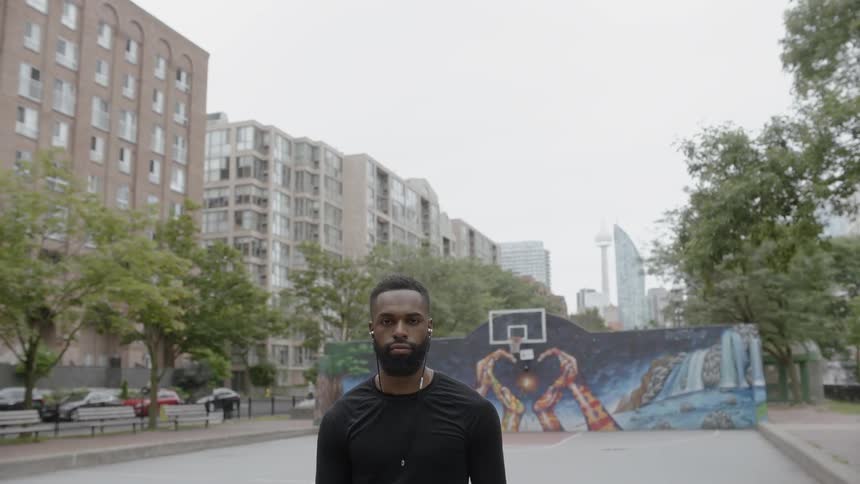 A man standing on an outdoor basketball court in the daytime