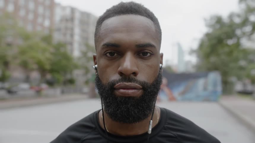 Man wearing earphones stands staring