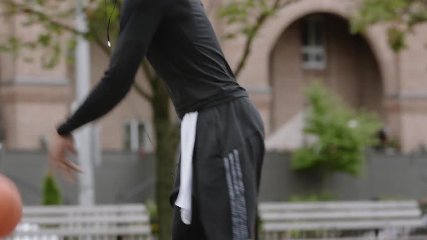Man walks across a court dribbling a basketball