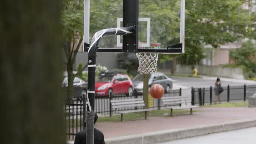 A man plays basketball alone on a neighborhood court