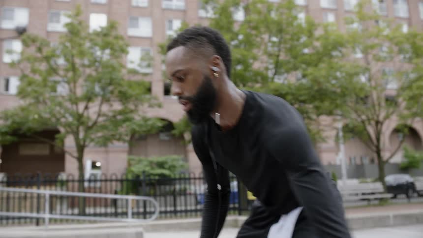 A black man dribbling and shooting a basketball on an outdoor court during the day