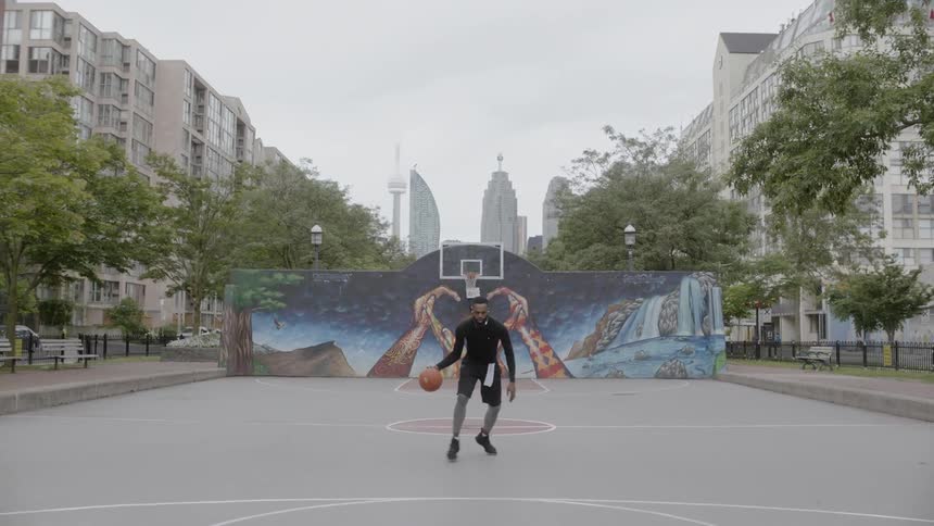 African american man dribbles basketball on outdoor court and takes shot