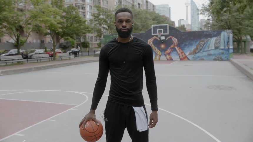 African american man stands on outdoor basketball court with basketball