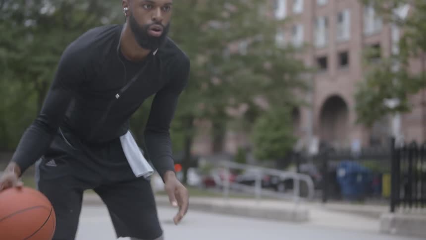 Black man training basketball in a public basketball court