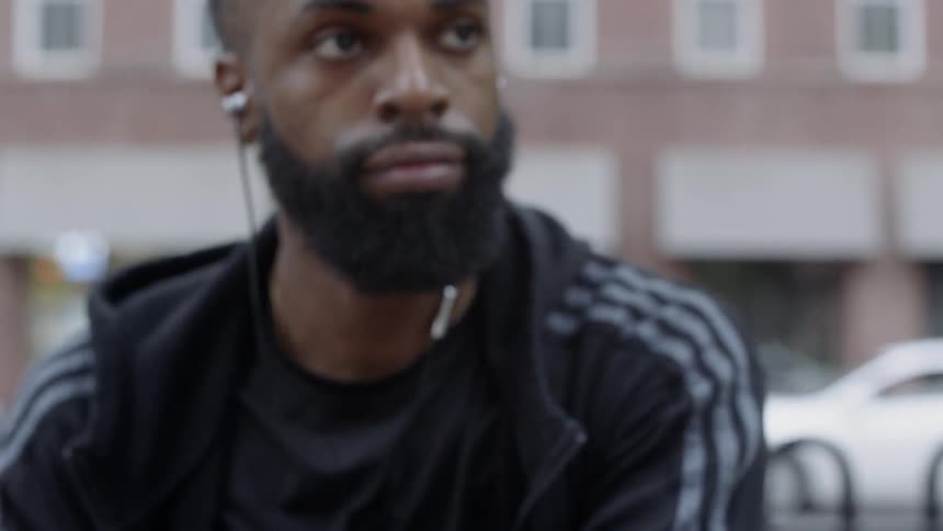 Man listens to earbuds while he takes off his sweater