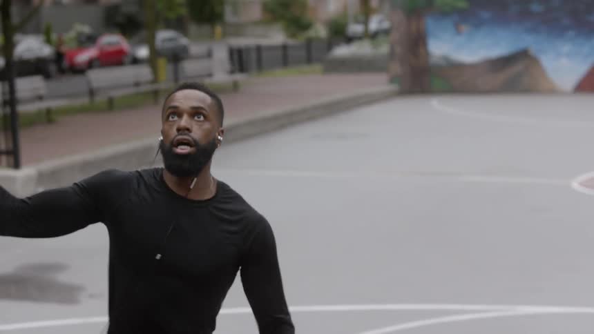 Man dribbles a basketball and goes for a lay up on a court