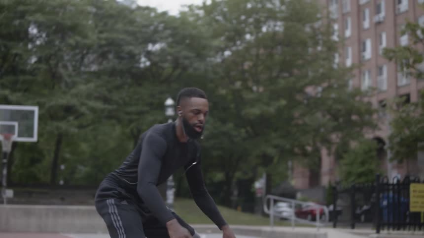 Man bounces a basketball on a court then makes a shot
