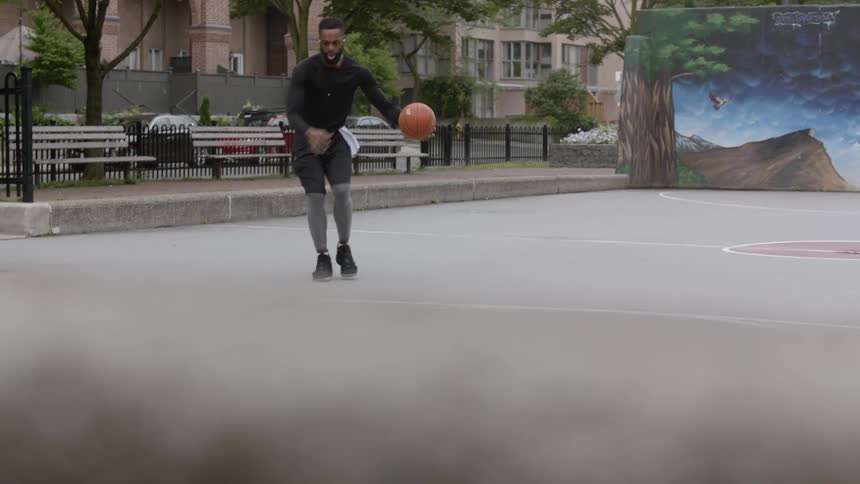 The black man dribbles and then tries to make the basket at the inter city court