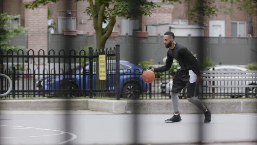 A young black man dribble and tosses a basketball