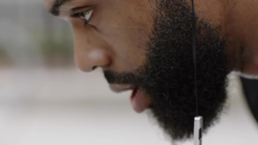 A black man breathes deep and relaxes after some sort of physical activity