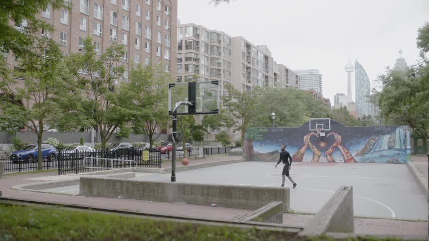 Man playing basketball alone on a court in a public park