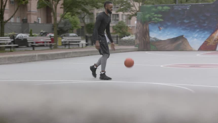 Man dribbles a basketball on a court then shoots it