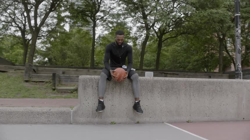 A black man holding a basketball net a basketball court