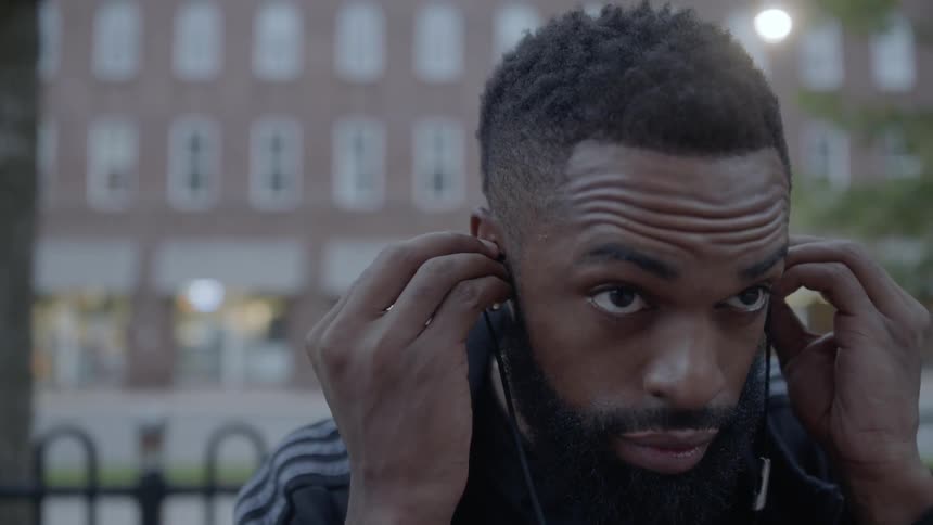 A man putting headphones on while standing on a city street