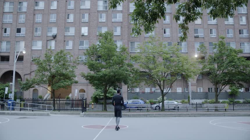 A man walks across the court with a basketball