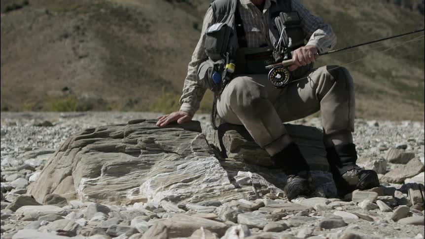 Fisherman sits down on a rock