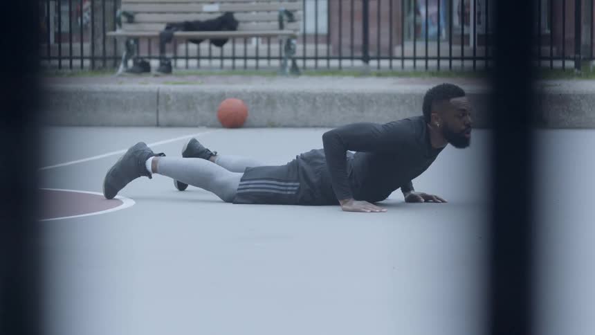 Bearded black man warms up in the middle of basketball field in the daytime