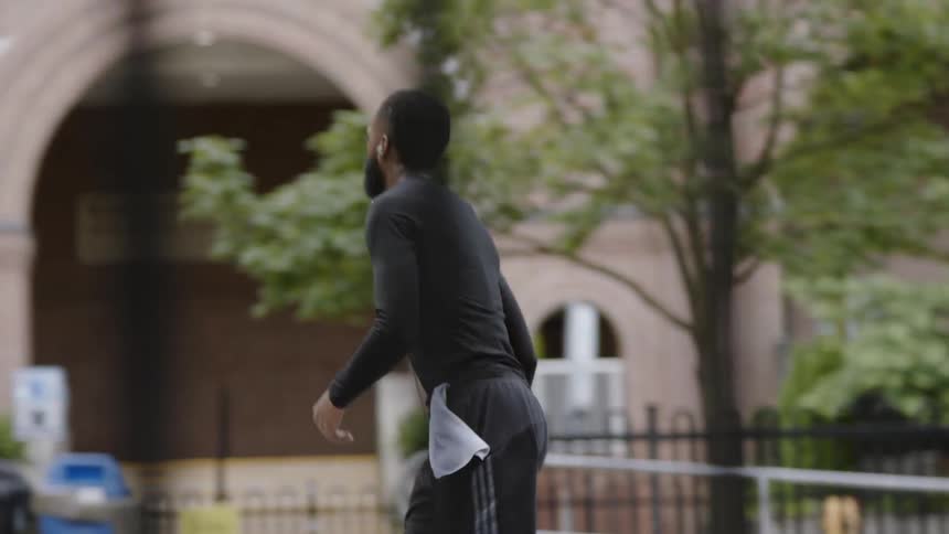 A young black man tosses a basketball towards the net