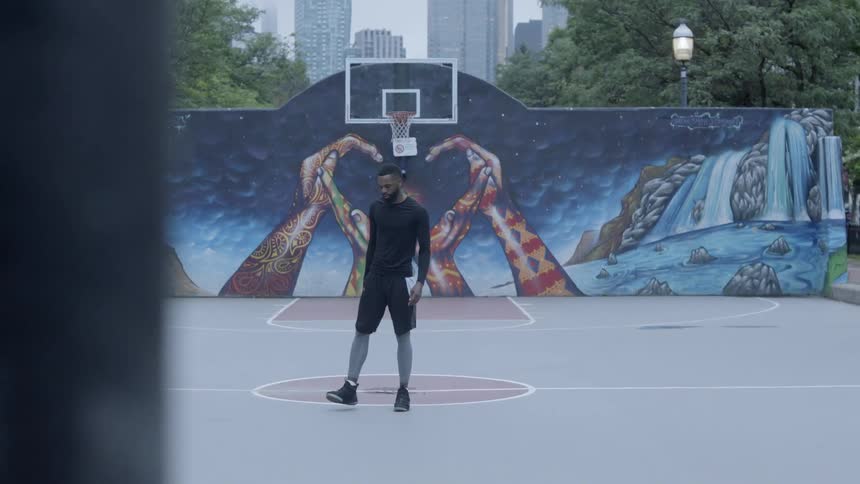 Man stretches on basketball court with painted wall
