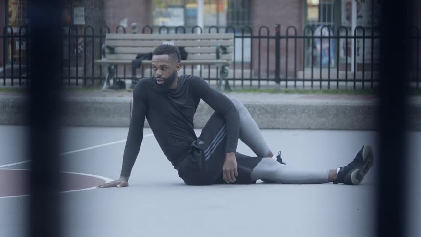 Bearded black man warms up in the middle of basketball field in the daytime