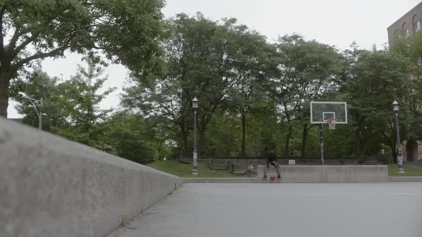 A teenager bounces a basketball at the park